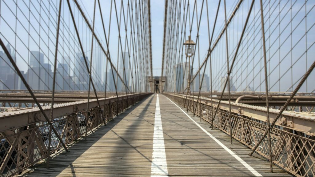 USA New York, Brooklyn bridge made of steel and cable. Empty famous footbridge, skyscraper blue sky.