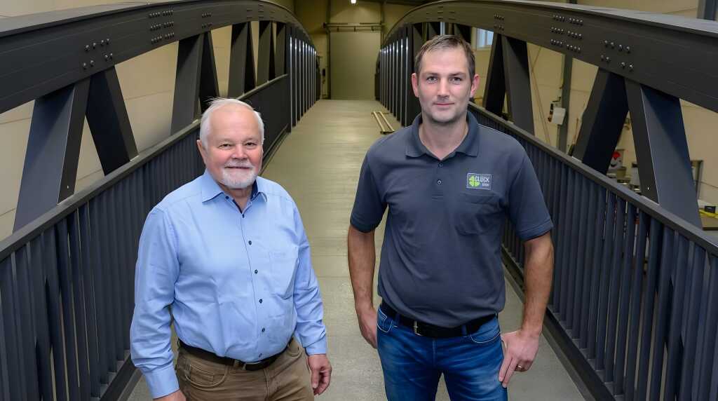 Werner Glück und Andres Weh auf einer Aluminiumbrücke in der Werkshalle posierend für das Foto