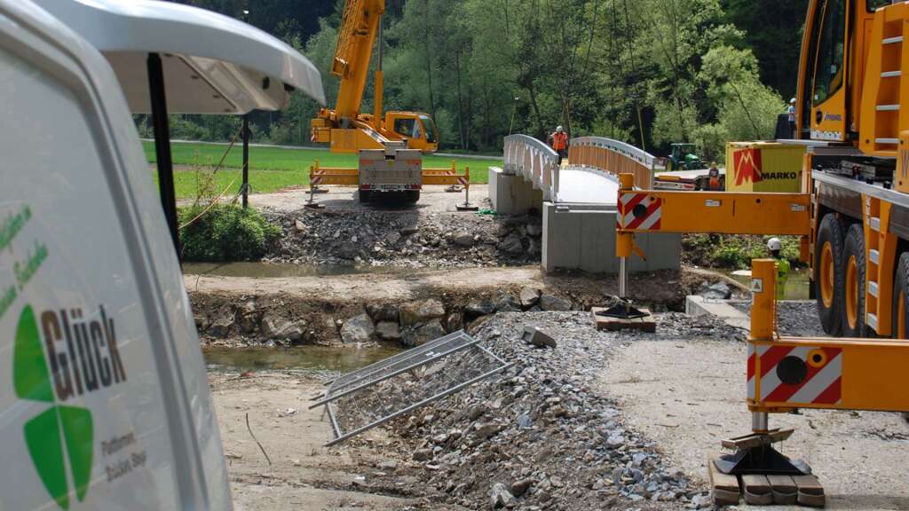 Zwei Kräne heben gemeinsam eine 18,50 Meter lange Aluminium-Radwegbrücke an