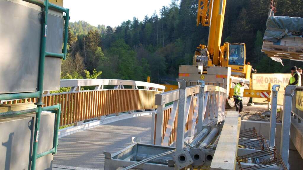 Fertig eingehobene Aluminium-Radwegbrücke über den Falkenbach mit Mobilkran auf der Baustelle