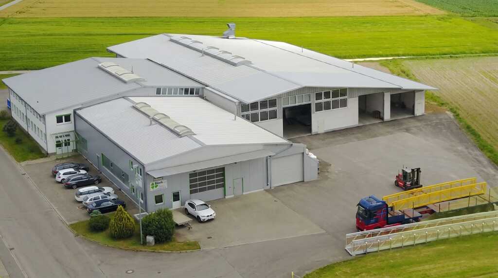 Vogelperspektive auf das Werk der Glück GmbH mit Werkhallen und Außenbereich.